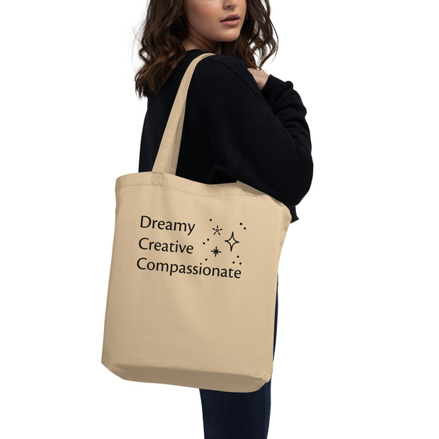 Beige tote bag with text held by a person on a white background