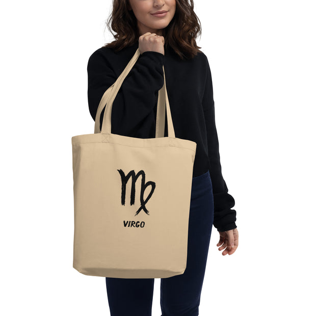 Person holding a beige tote bag with 'Virgo' and zodiac symbol on a white background