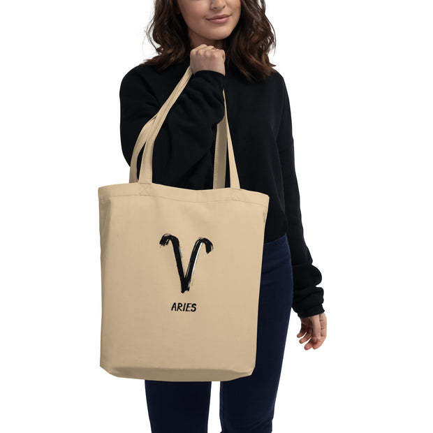 Person holding a beige tote bag with Aries symbol and name