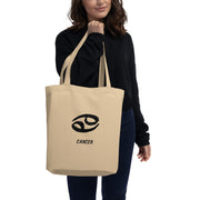Person holding a beige tote bag with 'Cancer' zodiac symbol on a white background