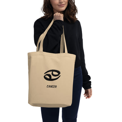 Person holding a beige tote bag with 'Cancer' zodiac symbol on a white background