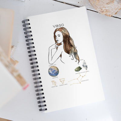 Notebook with Virgo zodiac illustration on a white surface