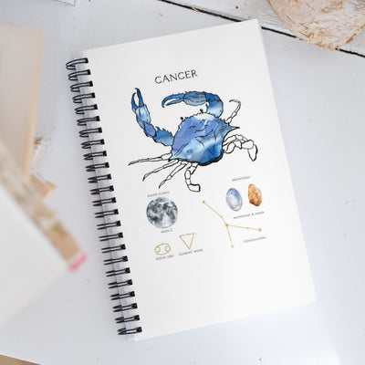 Notebook with Cancer zodiac illustration on a white surface