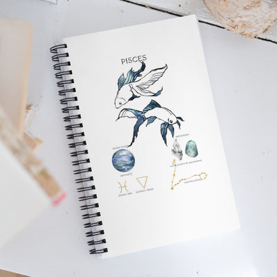 Notebook with Pisces zodiac design on a white surface