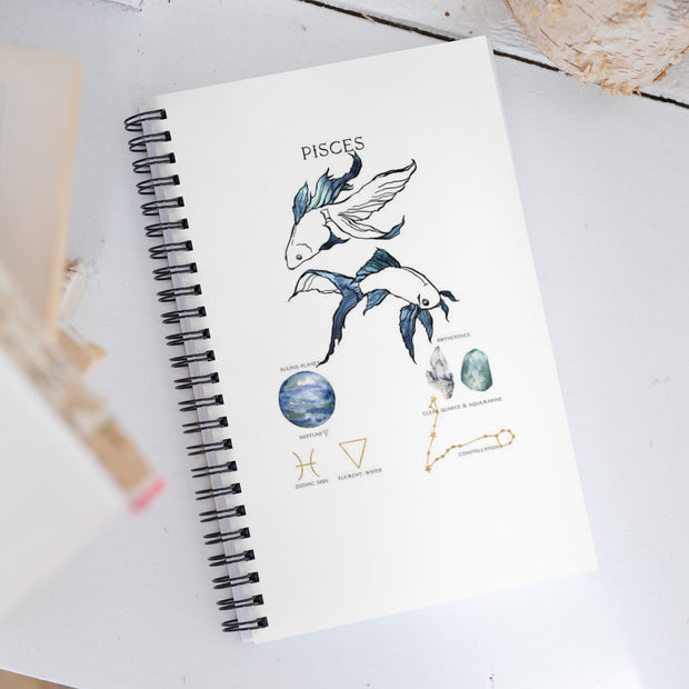 Notebook with Pisces zodiac design on a white surface