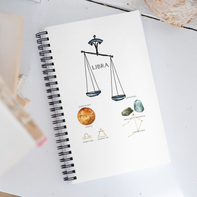 Notebook with Libra zodiac sign illustration on a white surface