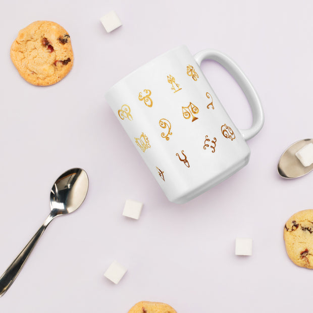 White mug with gold symbols, cookies, and a spoon on a light purple background
