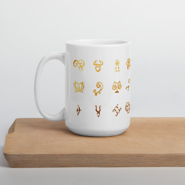 White mug with gold astrological symbol designs on a wooden surface