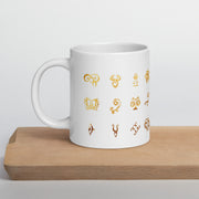 White mug with gold astrological symbol designs on a wooden surface